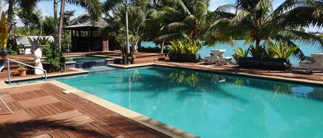 Una piscina al aire libre, sillones reclinables de piscina