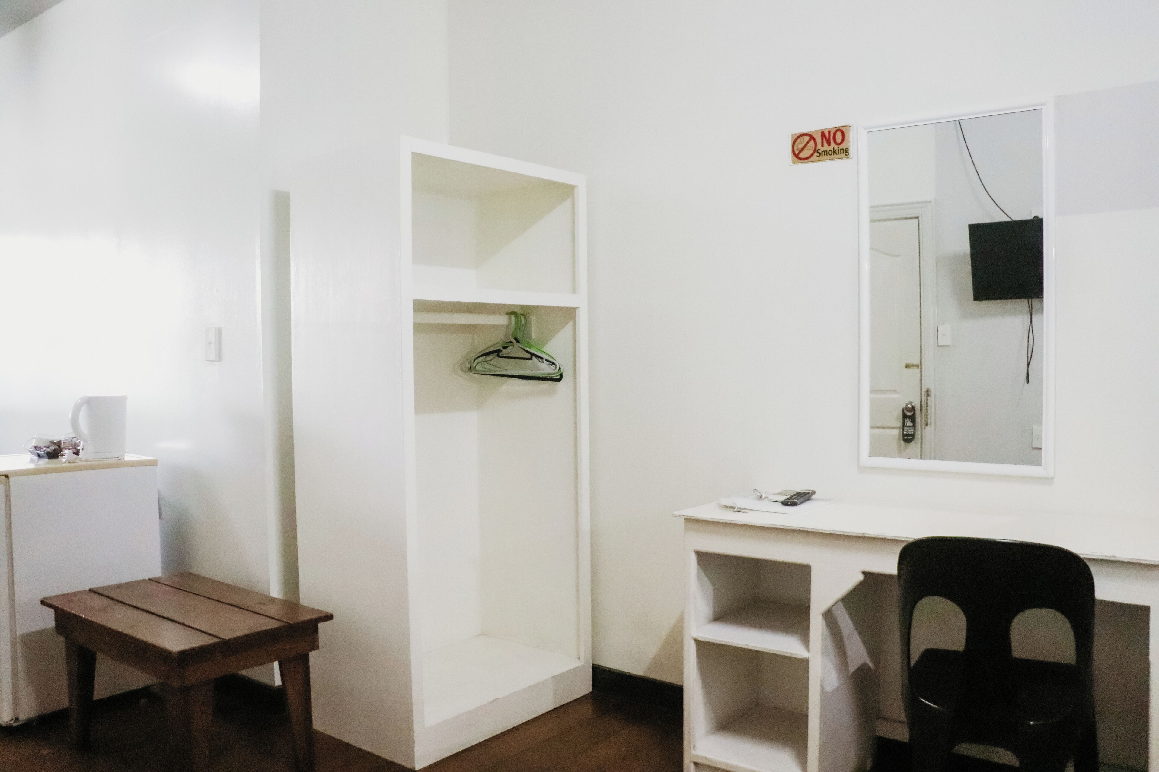 A small, clean room with a desk, chair, and a white wardrobe.