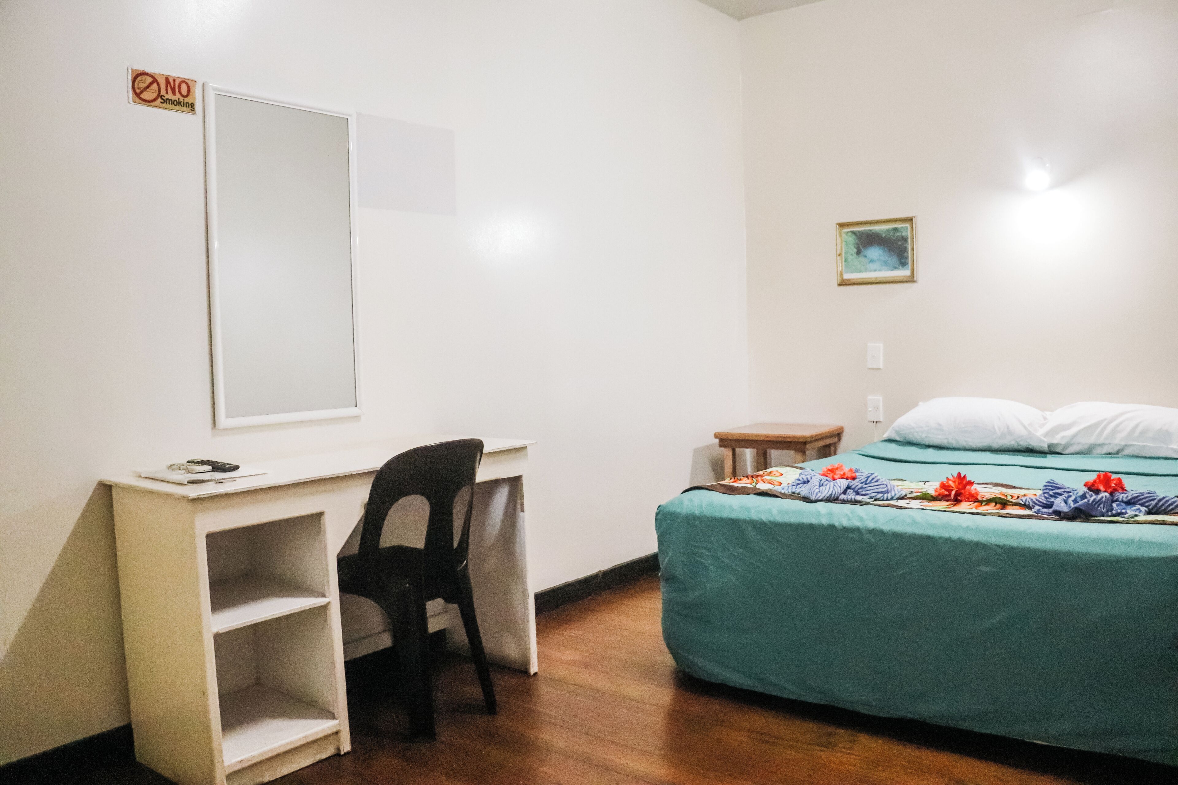 A room with a desk, chair, bed, and a small table.