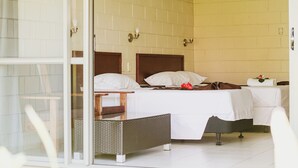 Ett hotellrum med två sängar, en entré med en glasdörr och ett litet bord.