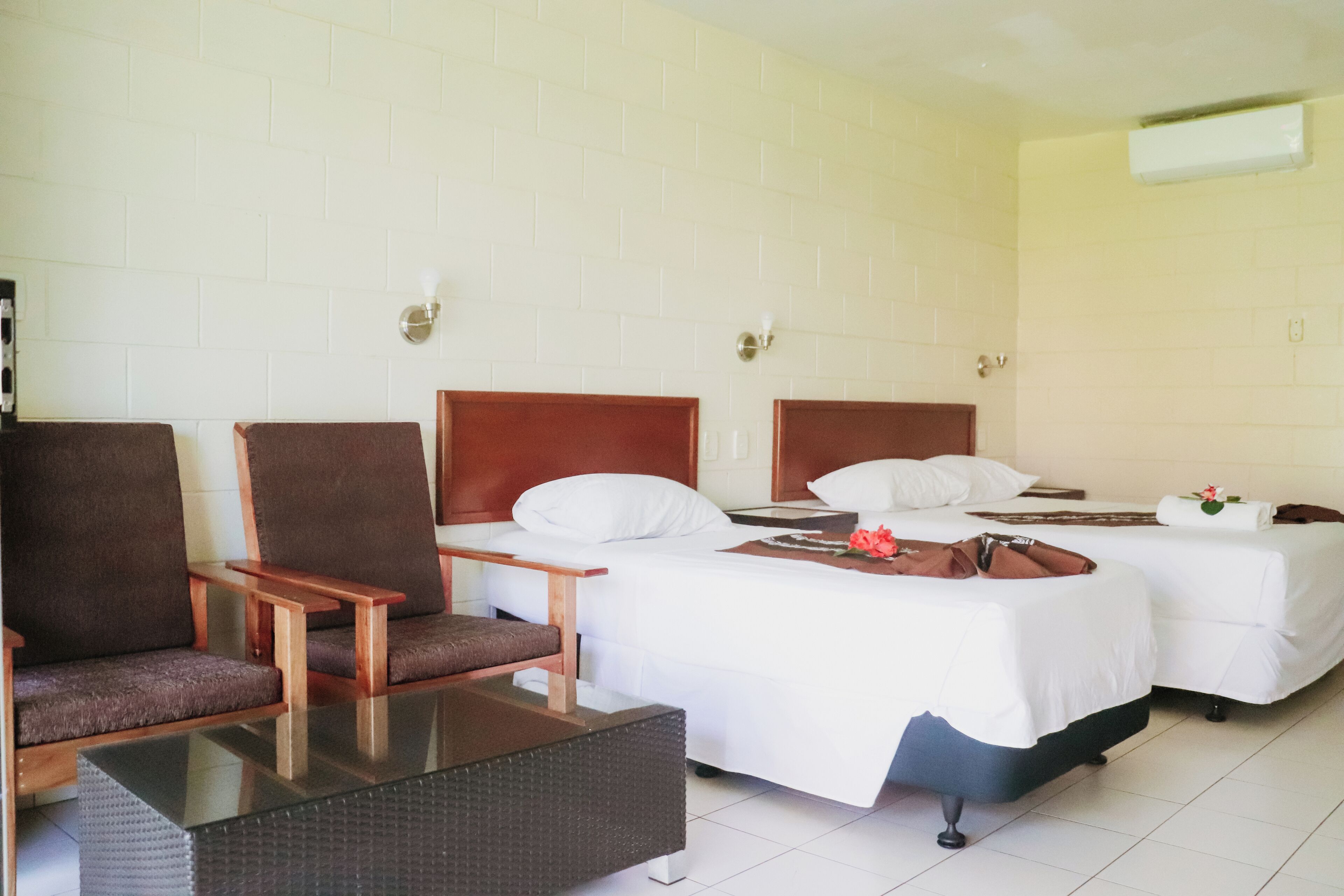 A hotel room with two beds, a sofa, a small table, and a chair.