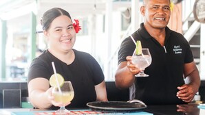 En bardisk med två personer, varav en håller i ett glas med en limeskiva i.