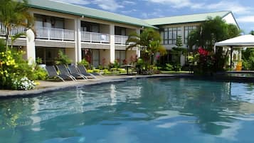 A hotel with a swimming pool, balconies, and tropical landscaping.