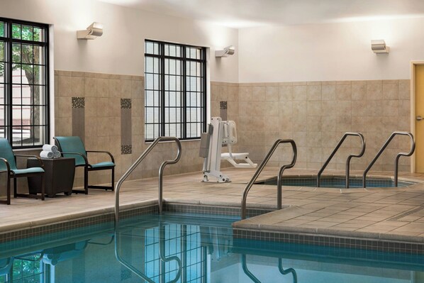Une piscine dotée d’une terrasse carrelée, de chaises longues et d’équipements de musculation.