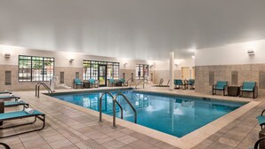 Une grande piscine intérieure entourée de chaises longues et de transats.