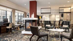 Un hall d’hôtel doté d’une cheminée, d’un coin salon et d’un téléviseur.