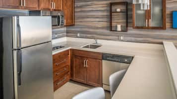 A modern kitchen with stainless steel appliances, wooden cabinets, and a marble backsplash.