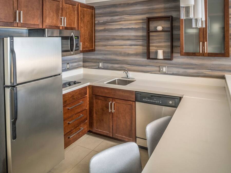 A modern kitchen with stainless steel appliances, wooden cabinets, and a marble backsplash.
