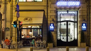 La façade de l’hôtel Cismigiu, avec son entrée imposante, un panneau indiquant un passage piéton et un espace extérieur aménagé avec des sièges.