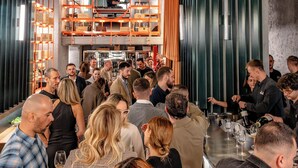 Un bar bondé, avec une cabine de DJ et des étagères remplies de bouteilles.