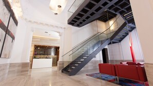 Un hall d’entrée spacieux, doté d’un escalier moderne, d’un comptoir de réception et d’un espace détente.