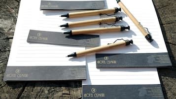 A wooden table with several black and gold hotel name tags and matching pens.