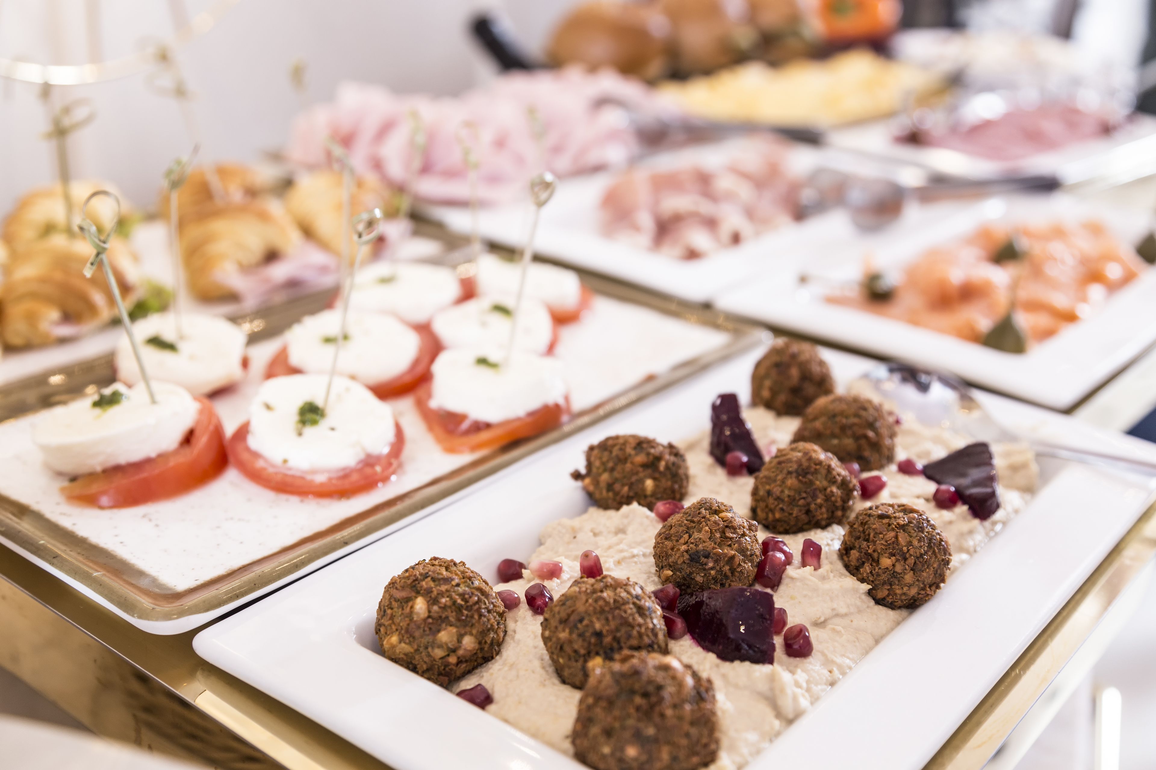 A buffet with various food items including croissants, cheese, and meat.