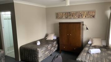A hotel room with two beds, a wardrobe, a desk, and a chair.