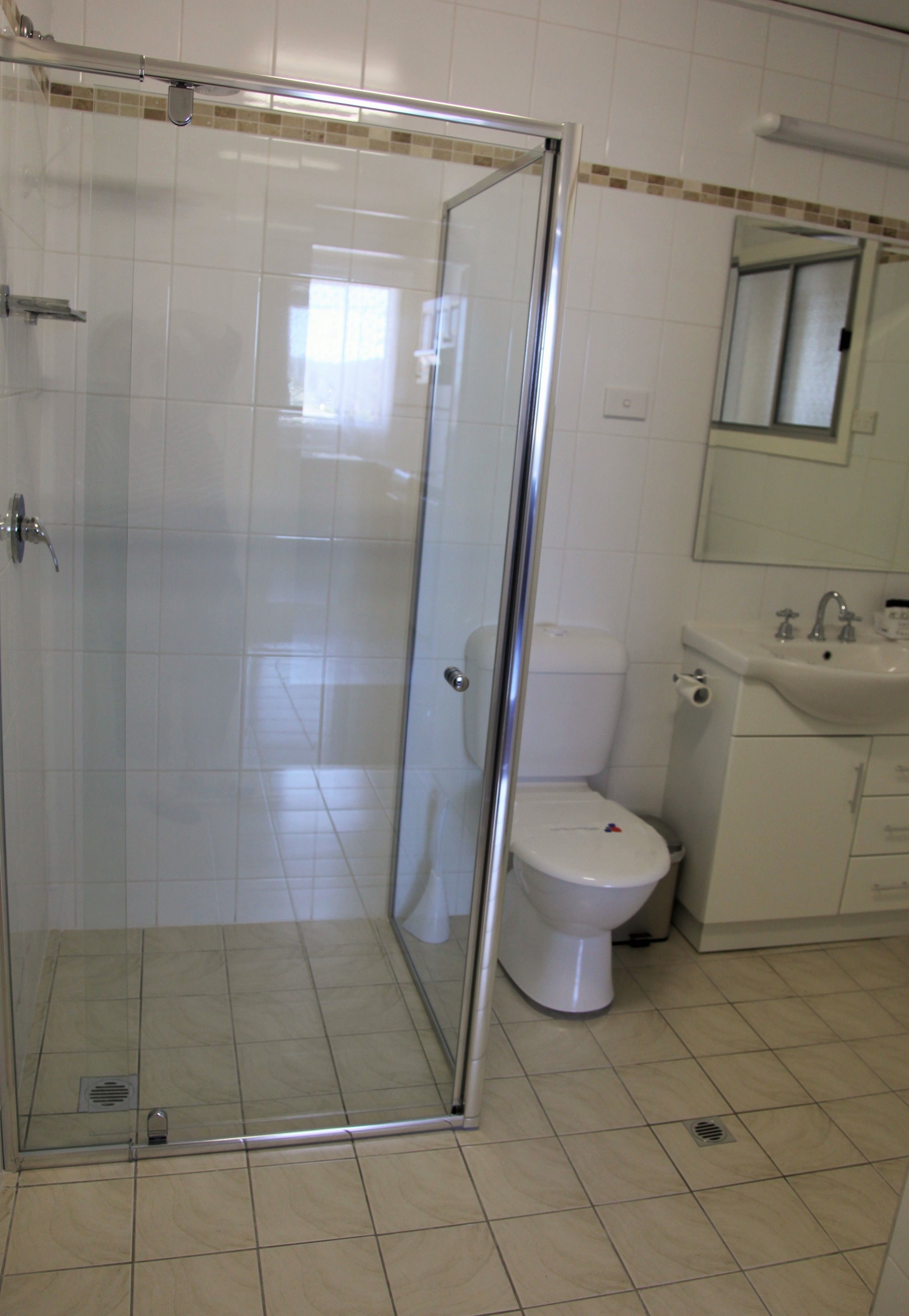 Un baño con ducha de vidrio, inodoro y lavamanos.
