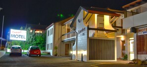 A motel with a large sign, a covered entrance, and two cars parked in front. - Barcelona Motel (Taupo)