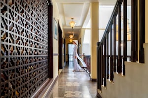 Un pasillo con paneles decorativos en la pared, una escalera y una persona caminando.