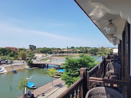 Un balcón con vista a un río, barcos y un puente.