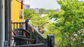 A balcony with wicker furniture, a red lantern, and a view of a river and buildings.