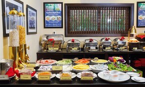 Ein Buffet mit verschiedenen Speisen und Beschriftungen, darunter frische Milch, Cocopop, Papayagemüse, Ananasgemüse und Erdbeermarmelade.