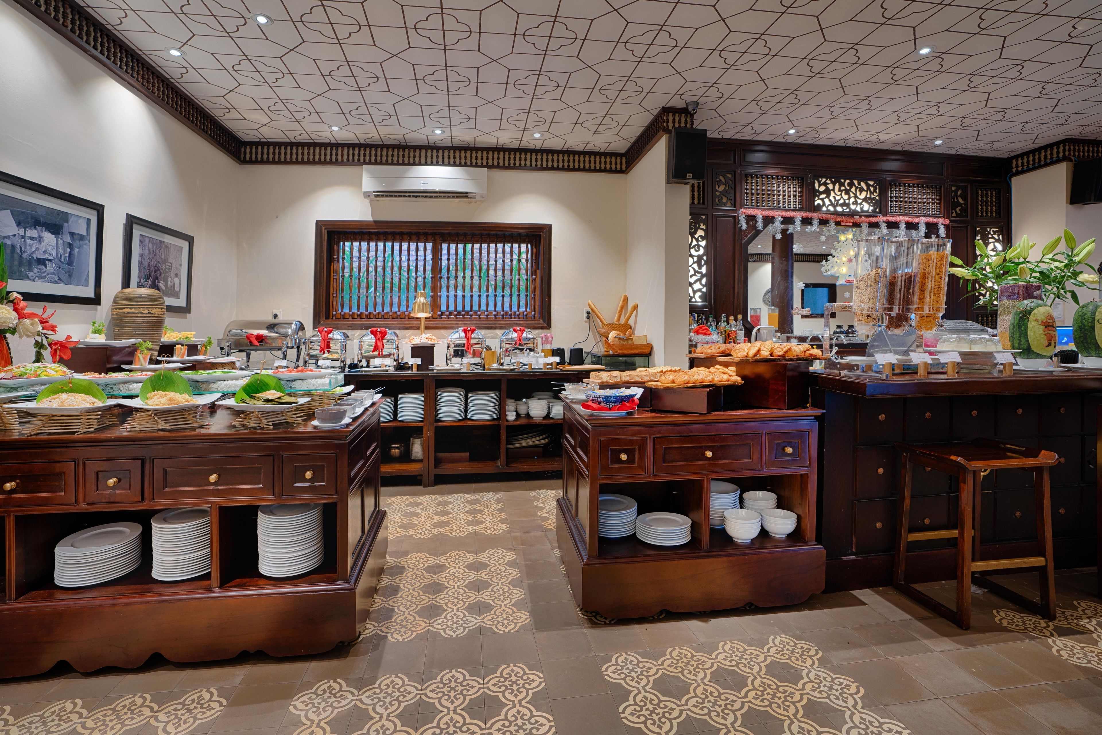 A buffet setup with multiple serving stations, a decorative ceiling, and a patterned floor.