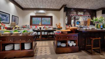 A buffet setup with multiple serving stations, a decorative ceiling, and a patterned floor.
