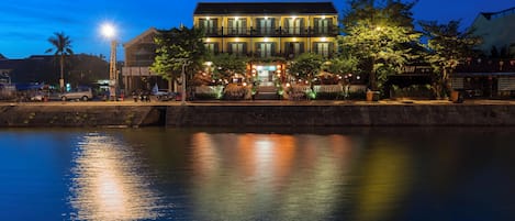 Ein Hotel am Wasserufer mit einem spiegelnden Pool, einem Balkon und einem Restaurant mit Außenbereich.