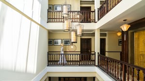 Een meerlaags interieur met een houten balustrade, een persoon in beweging en hangende lampen.