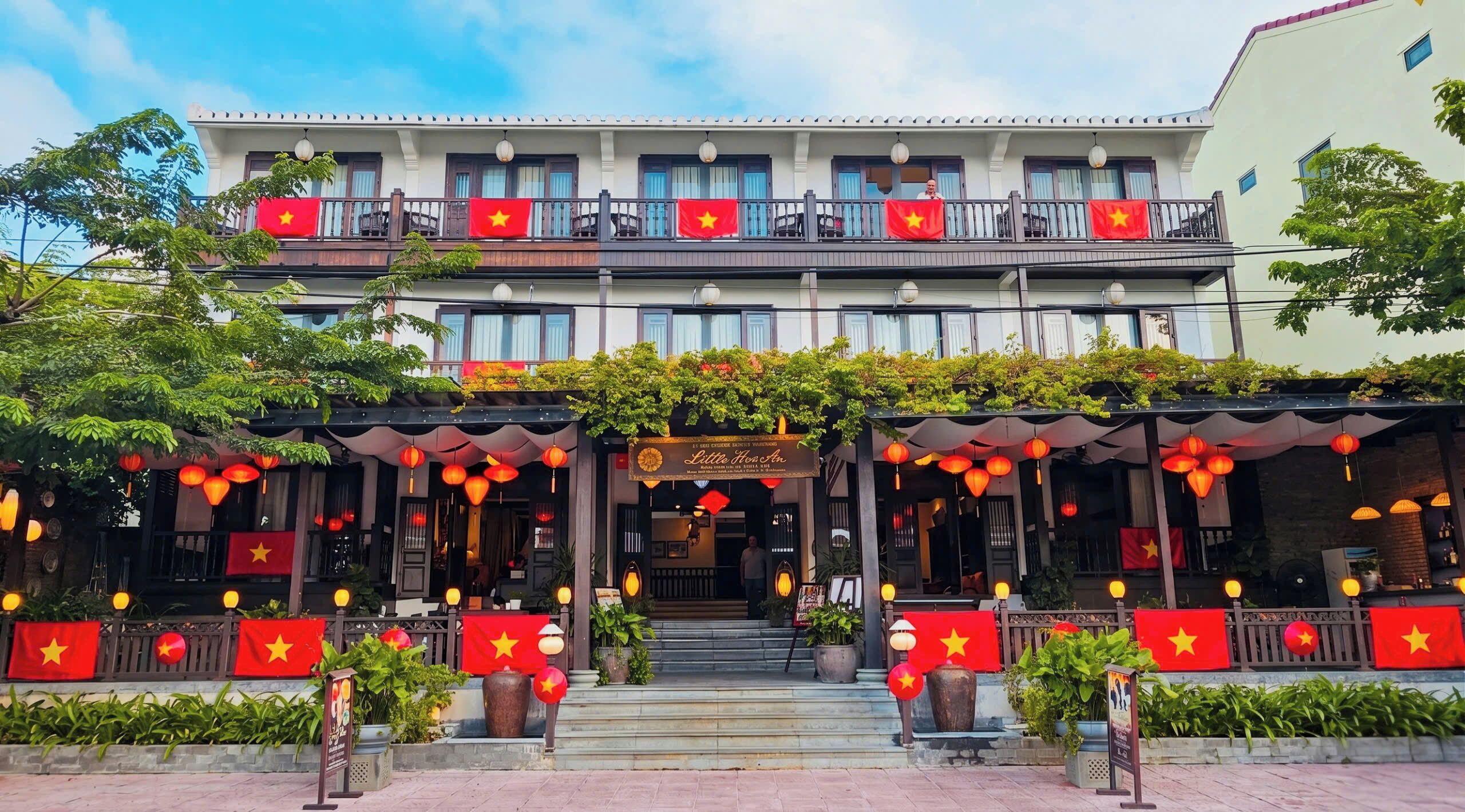 A hotel with a traditional facade, multiple balconies, and red flags.