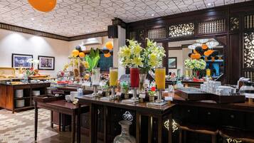 A hotel breakfast area with a buffet setup, a coffee station, and decorative elements like flowers and lanterns.