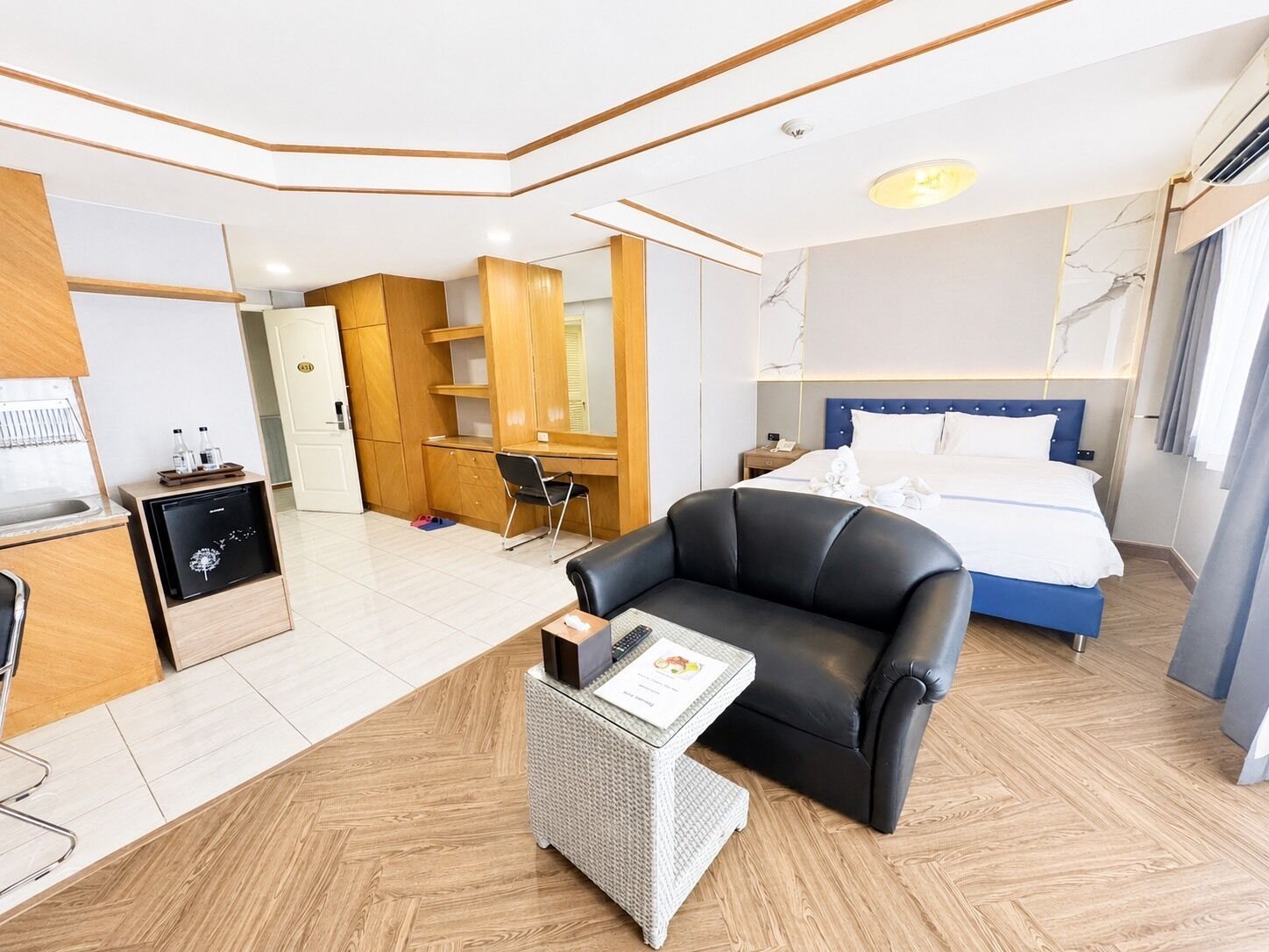 Une chambre d’hôtel moderne équipée d’un lit, d’un bureau, d’une chaise et d’une petite kitchenette.