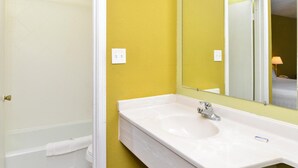 A bathroom with a white bathtub, a white sink, and a mirror.