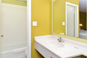 A bathroom with a white bathtub, a white sink, and a mirror.
