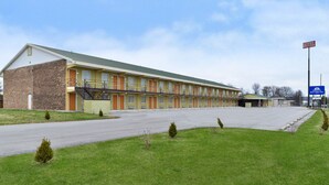 Ein Motel mit einer Reihe von eingeschossigen Zimmern, einem Parkplatz und einer kleinen Rasenfläche.