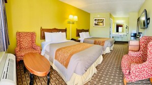 A hotel room with two beds, a desk, a chair, a television, and a bathroom.