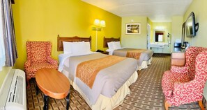 A hotel room with two beds, a desk, a chair, a television, and a bathroom.