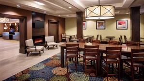 A hotel lobby with a fireplace, a television, and a dining area with multiple tables and chairs. - Holiday Inn Express & Suites Timmins by IHG (Timmins)