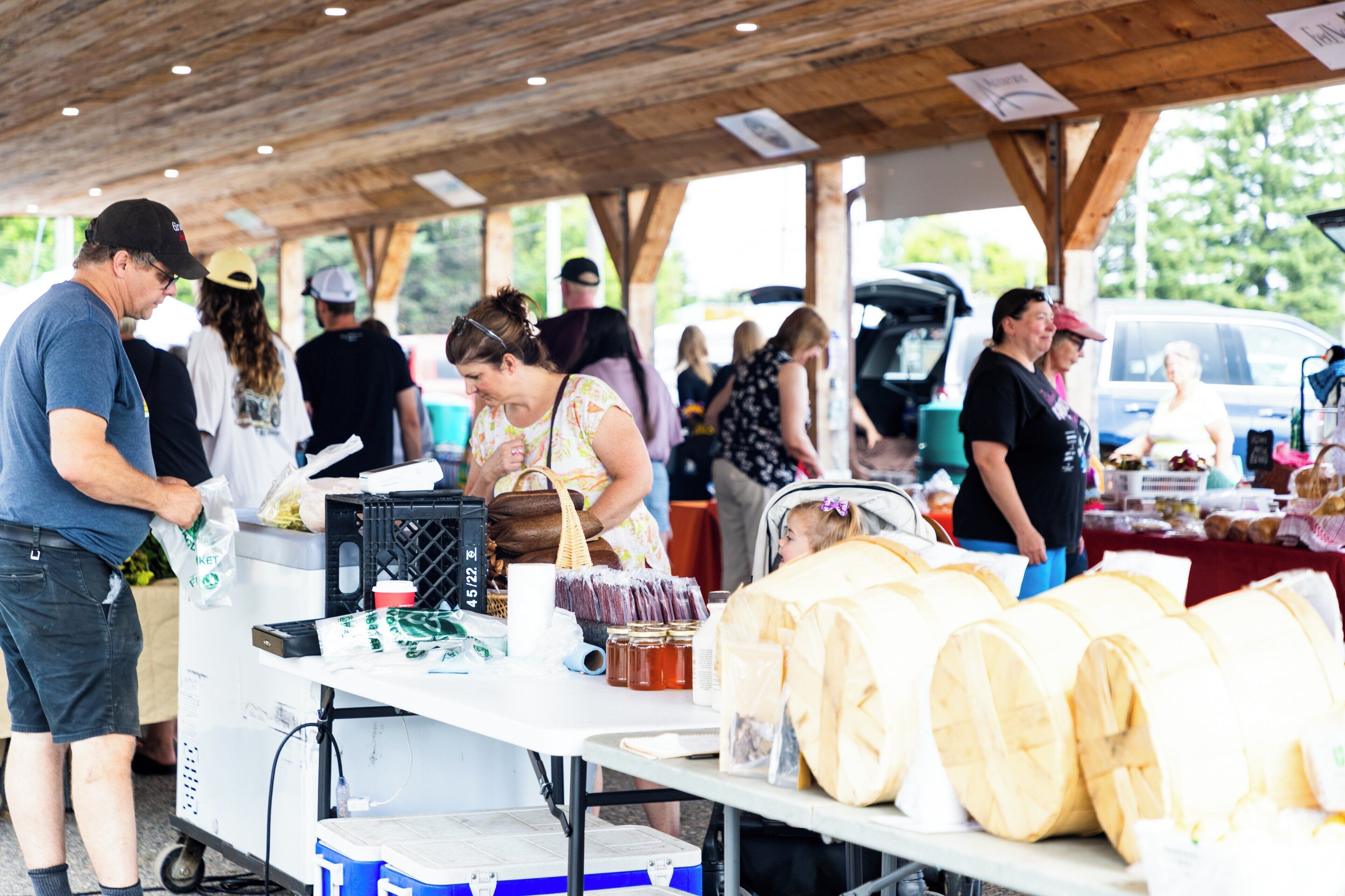 A covered outdoor market with people shopping and vendors selling goods.