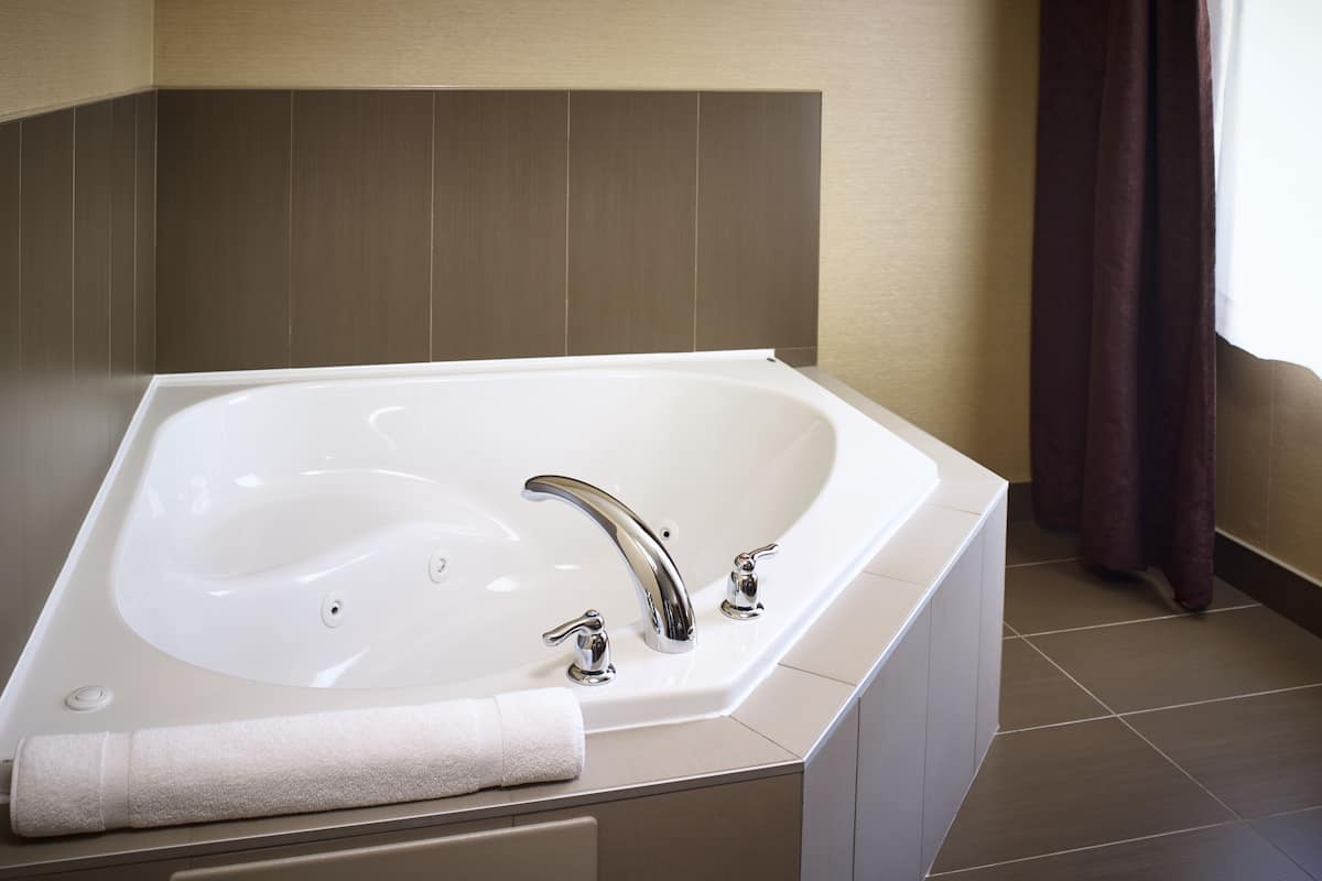 A modern bathroom with a large bathtub, a vanity with a mirror, and a towel placed on the edge.