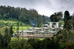 A cluster of traditional-style buildings with flat roofs, surrounded by lush greenery and terraced fields. - Sabol Holiday Resorts (Ootacamund)