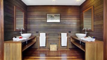 Bathroom features two sinks, a central bench, and a framed picture.
