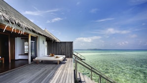 A wooden deck with a thatched roof, a lounge area with a sofa and table, and a view of the ocean. - Gangehi Island Resort (Gangehi Island)
