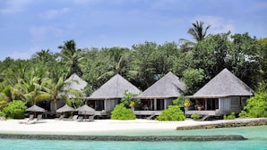 Overwater bungalows with thatched roofs, lounge chairs, and a clear view of the turquoise sea. - Gangehi Island Resort (Gangehi Island)