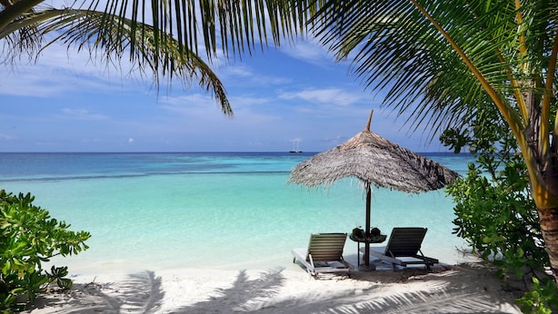 A beach with a thatched umbrella, two lounge chairs, and a clear view of the ocean. - Gangehi Island Resort (Gangehi Island)