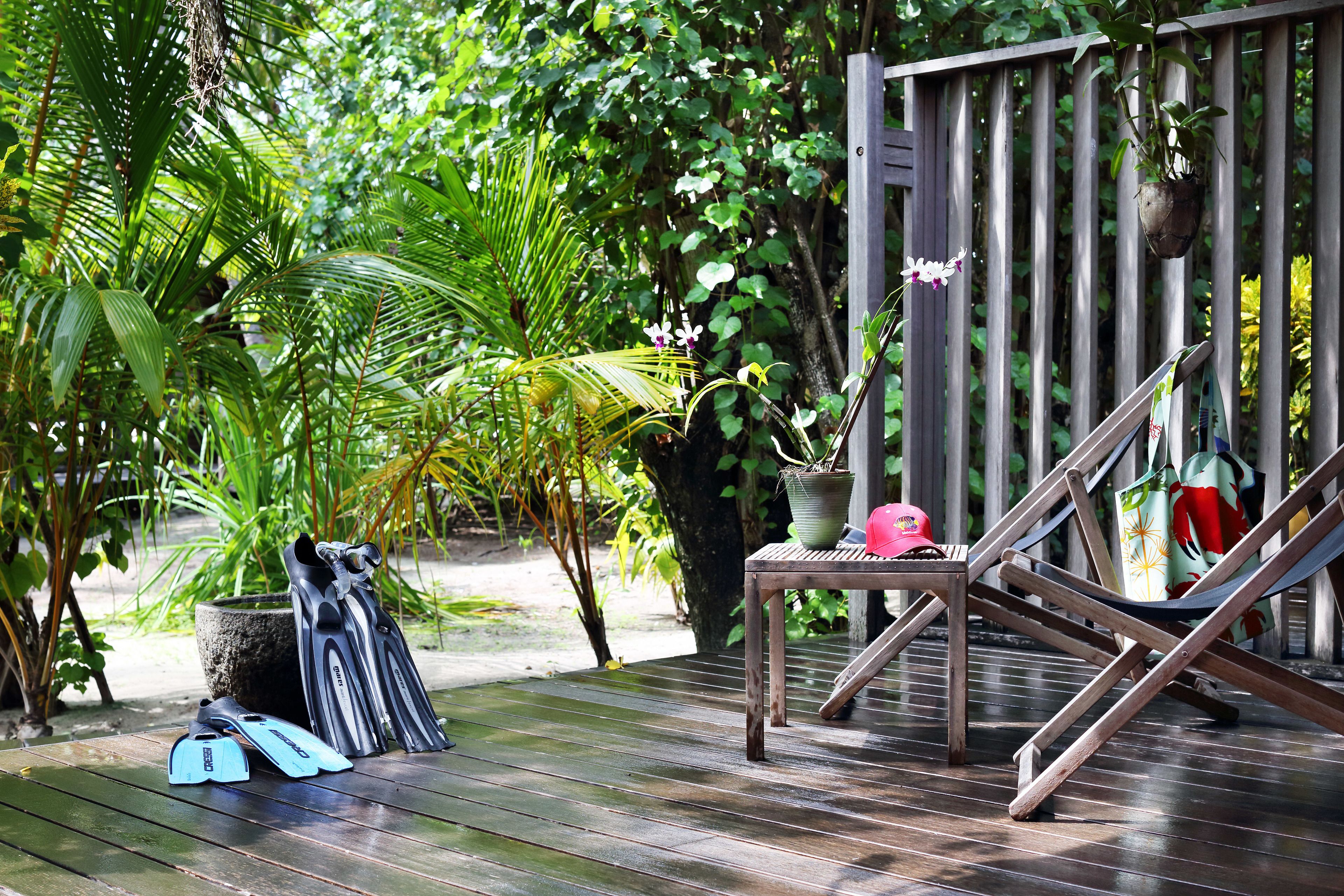 A wooden deck with a hammock, a table, and a potted plant.