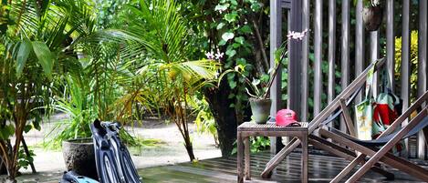A wooden deck with a hammock, a table, and a potted plant.