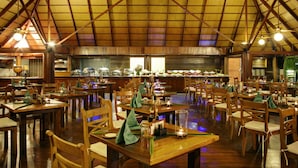 A spacious restaurant with wooden tables and chairs, a high ceiling, and a buffet area in the background. - Gangehi Island Resort (Gangehi Island)