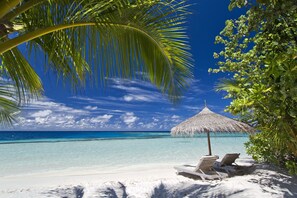 On the beach, white sand, sun-loungers, beach towels