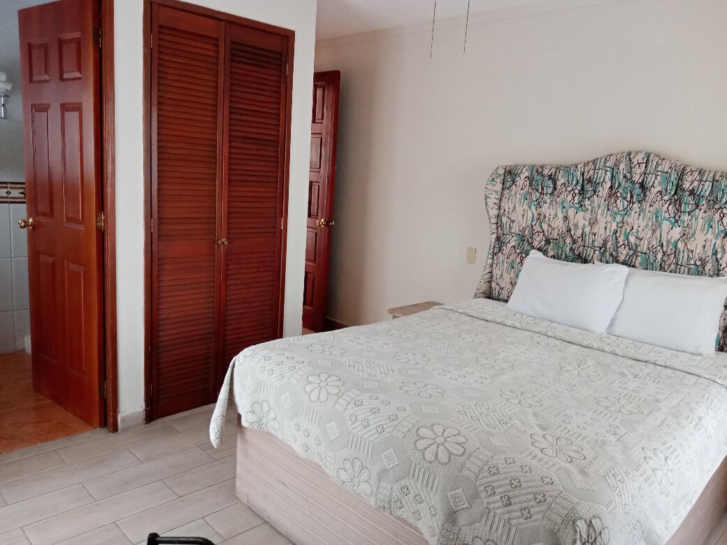 Un dormitorio con una cama, una mesita de noche, un armario de madera y un cabecero estampado.