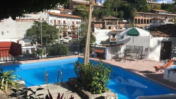 A swimming pool with a view of a residential area in the background. - Hotel Real de San Diego (Taxco)